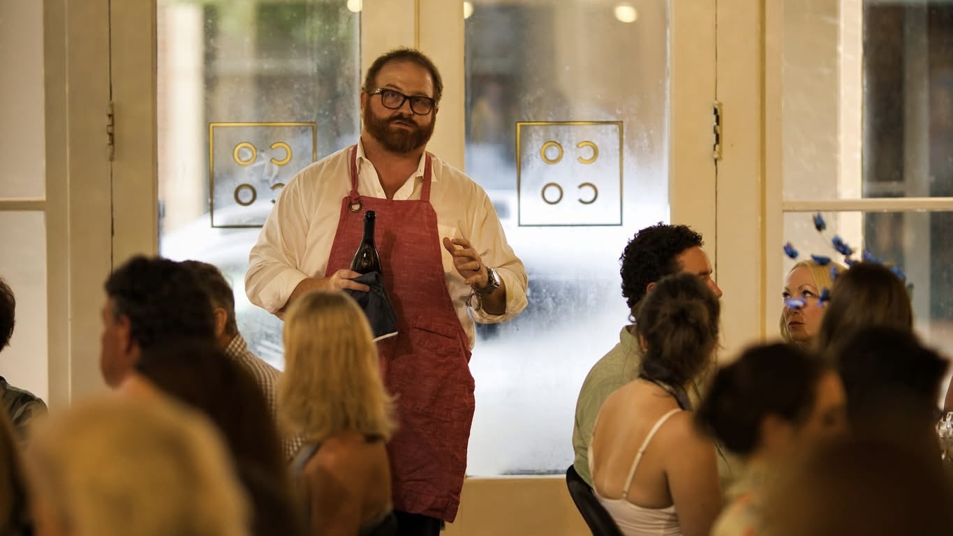 Wesley presenting wine at a dinner event
